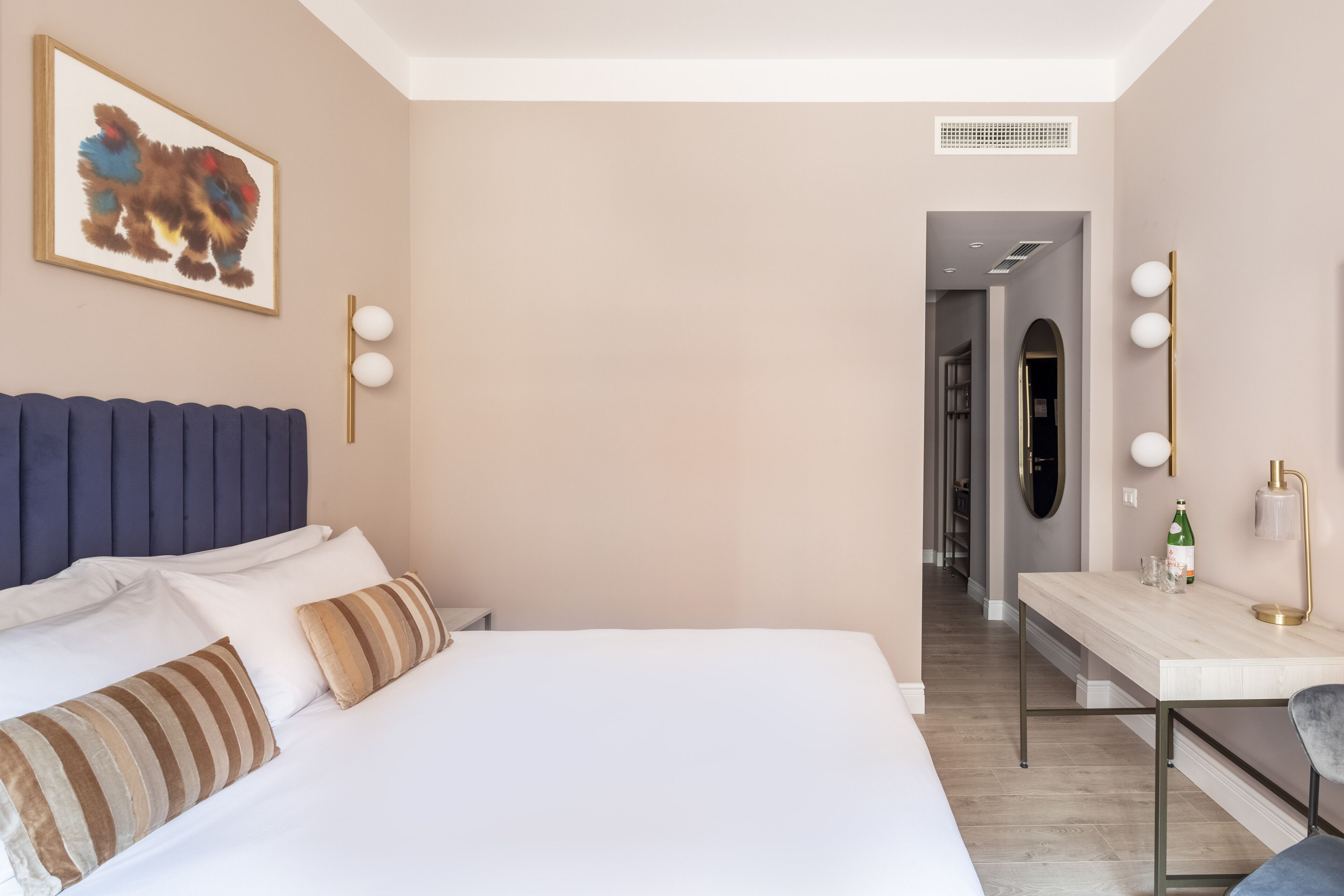 Ein modernes Hotelzimmer mit einem großen Bett, einem Schreibtisch mit Stuhl und einem Spiegel.