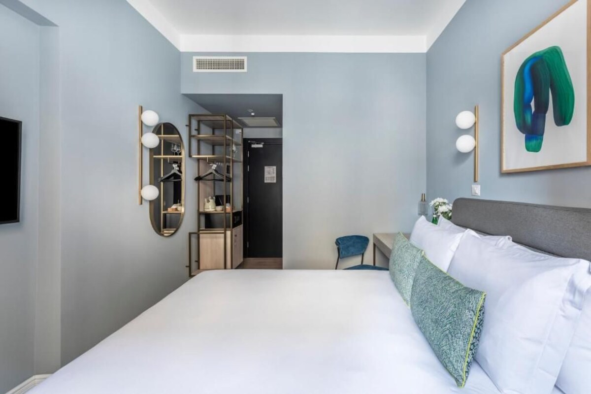 Una camera d'albergo con un letto, una scrivania, una sedia, un armadio e uno specchio.