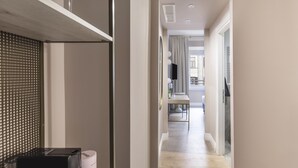 Un pasillo moderno de hotel con piso de madera, una pared de vidrio y un comedor al fondo.