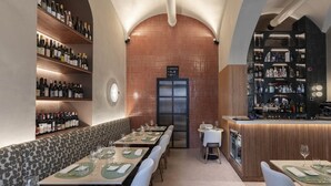 Un restaurante con mesas largas, una zona de bar y estantes llenos de botellas de vino.