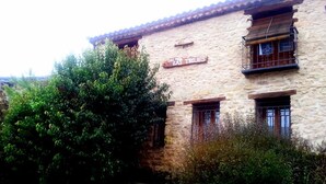 A stone building with a sign reading "CASA DE LOS TROJES" and a staircase leading to the entrance. - Casa Rural Las Trojes (Tamajon)