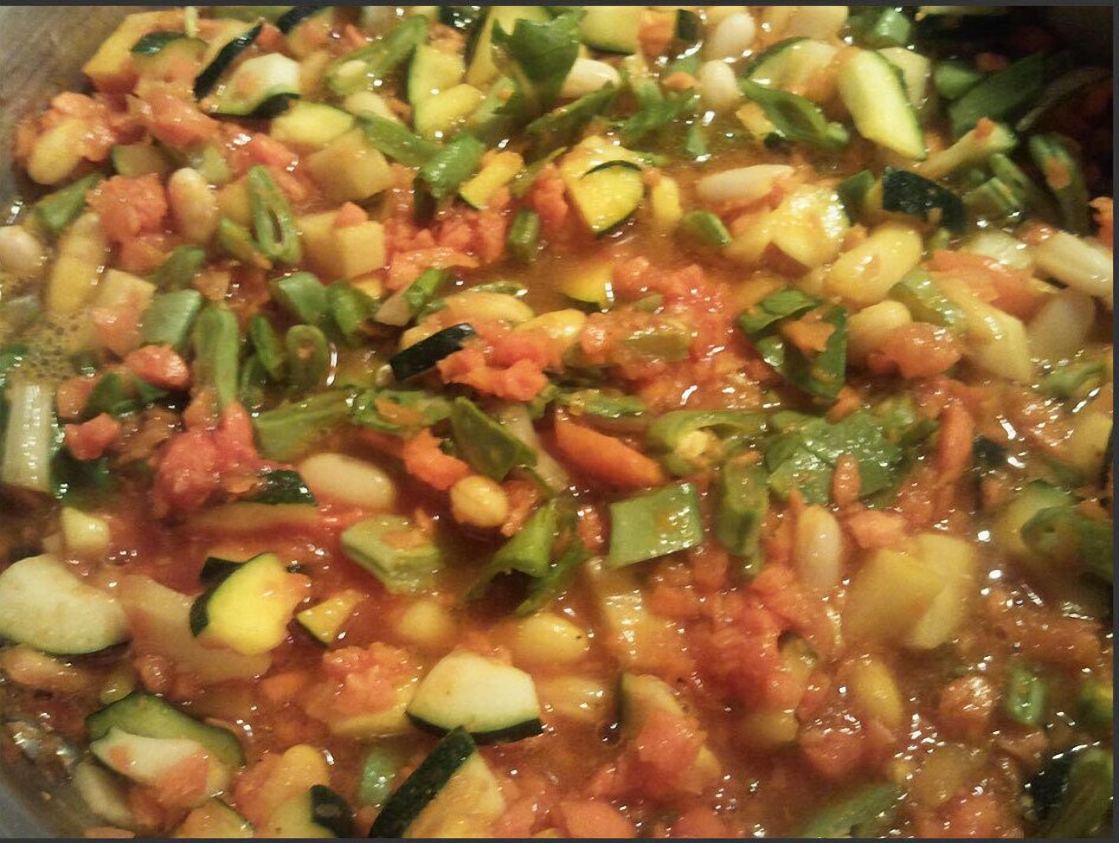 Primer plano de un guiso de verduras con diferentes vegetales como calabacín y tomates.