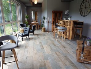 A spacious living area with a large window, a dining table, and several chairs. - Hotel Reich an der Rems (Schorndorf)