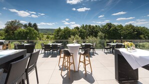 An outdoor patio with tables and chairs, overlooking a scenic landscape. - Hotel Reich an der Rems (Schorndorf)