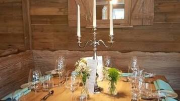 Een houten blokhut interieur met een eettafel gedekt voor zes personen, inclusief kaarsen, glazen en blauwe servetten.