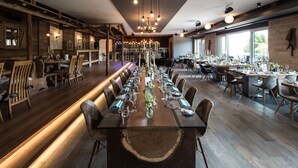A long dining table set for a meal in a spacious room with wooden flooring and modern lighting. - Hotel Reich an der Rems (Schorndorf)