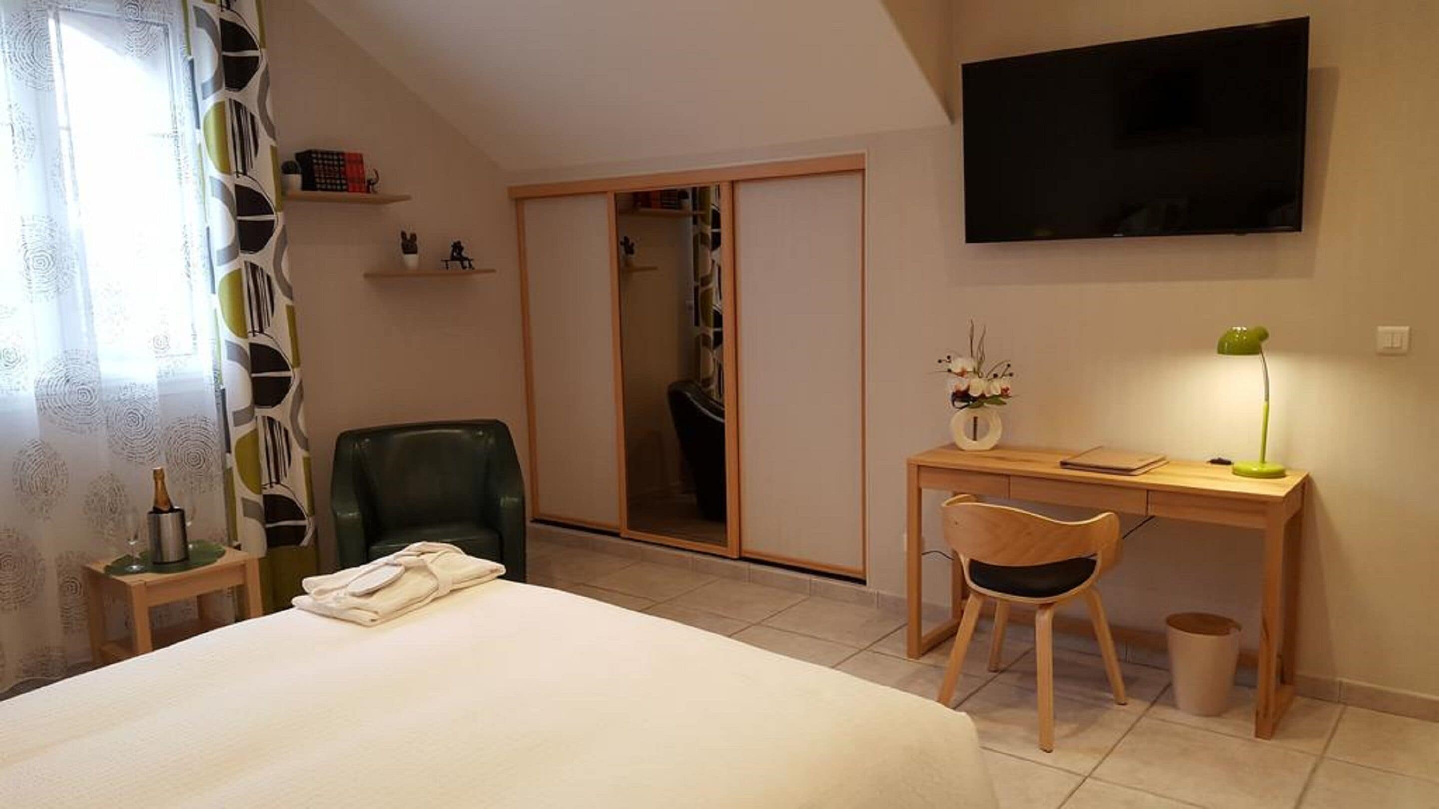 Een hotelkamer met een bed, een bureau met stoel, een televisie en een kledingkast.