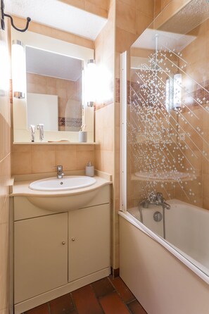 Une salle de bain avec un lavabo, un miroir et une douche.