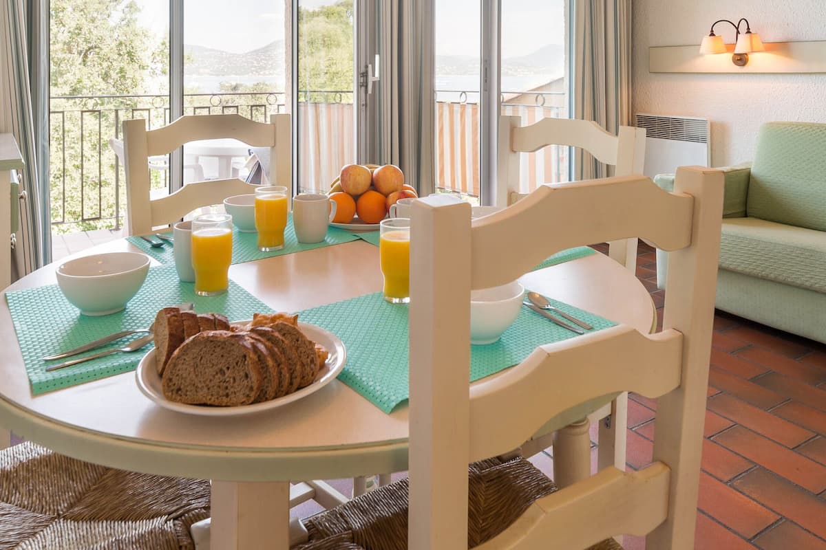 Un coin repas avec une table mise pour le petit-déjeuner, comprenant du pain, des fruits et du jus.