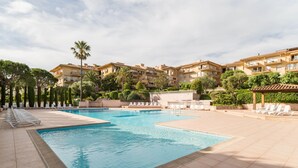 A swimming pool with lounge chairs, surrounded by apartment buildings and greenery. - Résidence Pierre & Vacances Baie de Saint-Tropez - Eden Parc (Saint-Tropez)