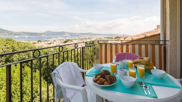 A balcony with a table set for breakfast, overlooking a coastal cityscape. - Résidence Pierre & Vacances Baie de Saint-Tropez - Eden Parc (Saint-Tropez)