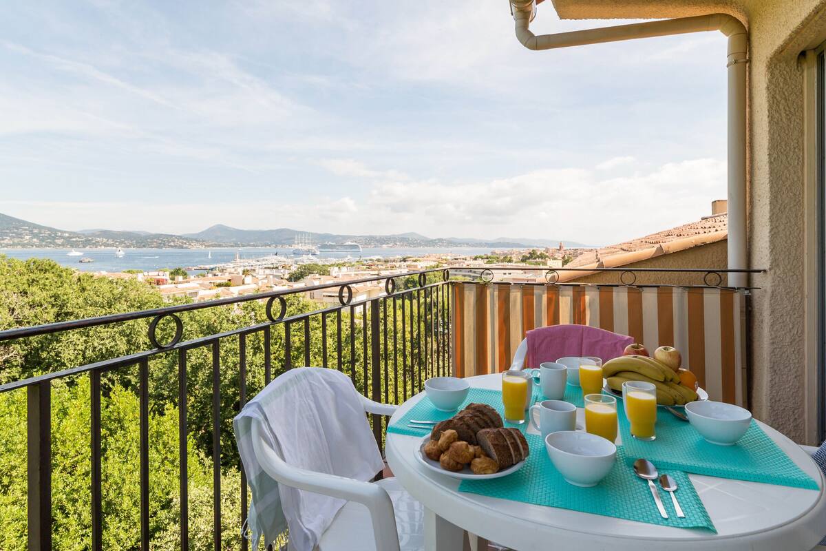 Un balcon avec une table préparée pour le petit-déjeuner, offrant une vue sur le paysage urbain de la côte.