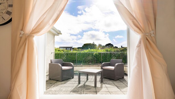 Un balcón con muebles de mimbre y vistas al cielo y al follaje.