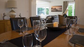 Una mesa de comedor dispuesta con copas de vino, una botella de champán y una vela.