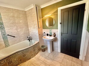 Un baño con bañera, lavabo y puerta.