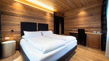 A modern bedroom with a wooden ceiling, a large bed, a bedside table, and a desk with a chair.