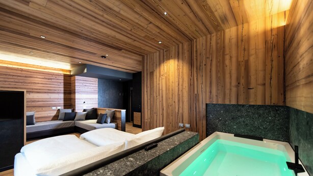 Een moderne hotelkamer met houten paneelwanden, een groot bad en twee bedden met witte lakens.