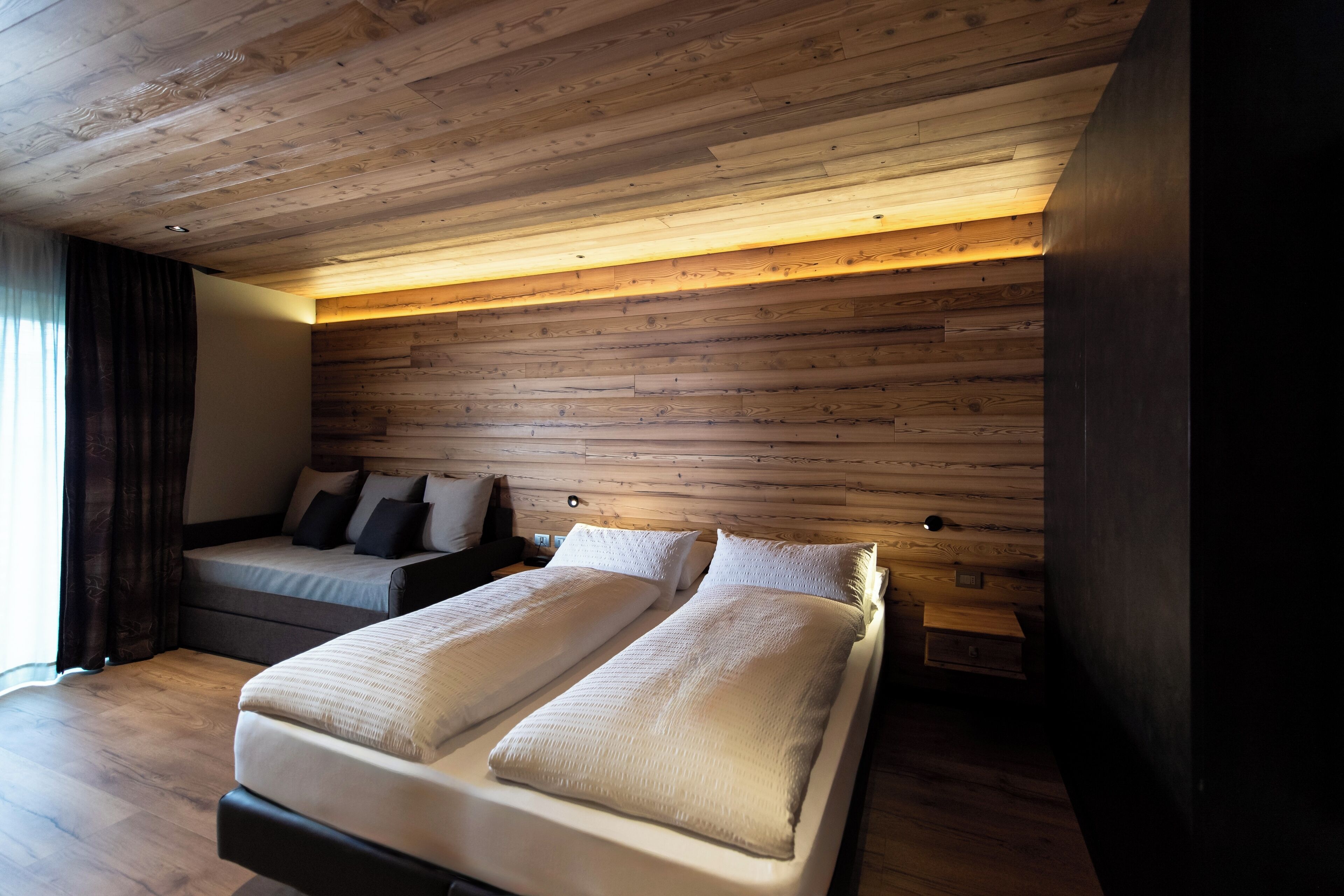 A bedroom with a wooden ceiling, two beds, and a nightstand.