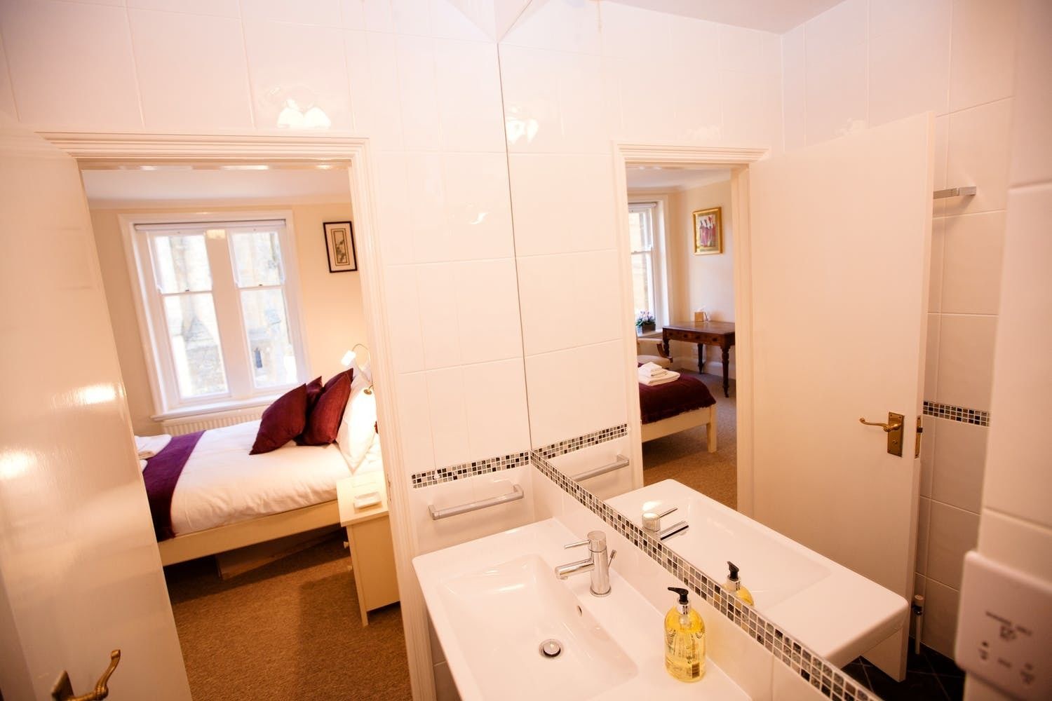 Une chambre d’hôtel de taille réduite, comprenant un lit, une salle de bain avec un lavabo et un miroir, et une petite table.