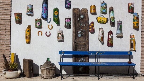 A wall with various decorative items, a blue bench, and a rustic door. - B&B Giuggiolando (L'Aquila)