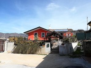Una casa rossa con cancello, un piccolo portico e una targa.