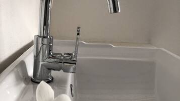 A bathroom sink with a chrome faucet, a white flower, and a towel.