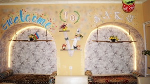 A room with two sofas facing each other, a 'Welcome' sign, a 'To' sign, and a 'Pet' sign. - Pegasus Hostel (Baku)