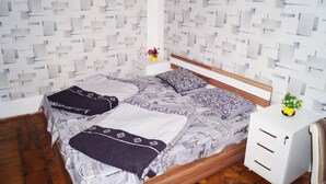 A neatly made bed with patterned bedding, a bedside table with a vase of flowers, and a white cabinet. - Pegasus Hostel (Baku)