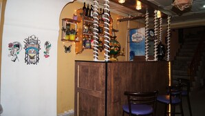 A bar area with wooden counter, hanging plants, and shelves with bottles. - Pegasus Hostel (Baku)