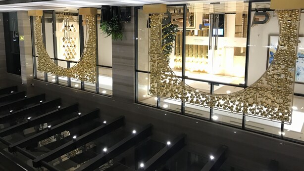 A modern interior with a glass storefront, metal railings, and a staircase leading to an upper level. - Mins Apartment - Vinhome Golden River (Ho Chi Minh City)