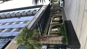 A modern building with a glass facade, a palm tree, and a Seven Eleven convenience store. - Mins Apartment - Vinhome Golden River (Ho Chi Minh City)