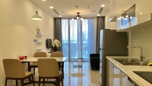 A modern kitchen with a stainless steel sink, a built-in oven, and a dining area with a table and chairs. - Mins Apartment - Vinhome Golden River (Ho Chi Minh City)