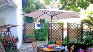An outdoor patio with a round table, wooden chairs, and a large umbrella. - B&B Villa Cinque Pini (Casamicciola Terme)