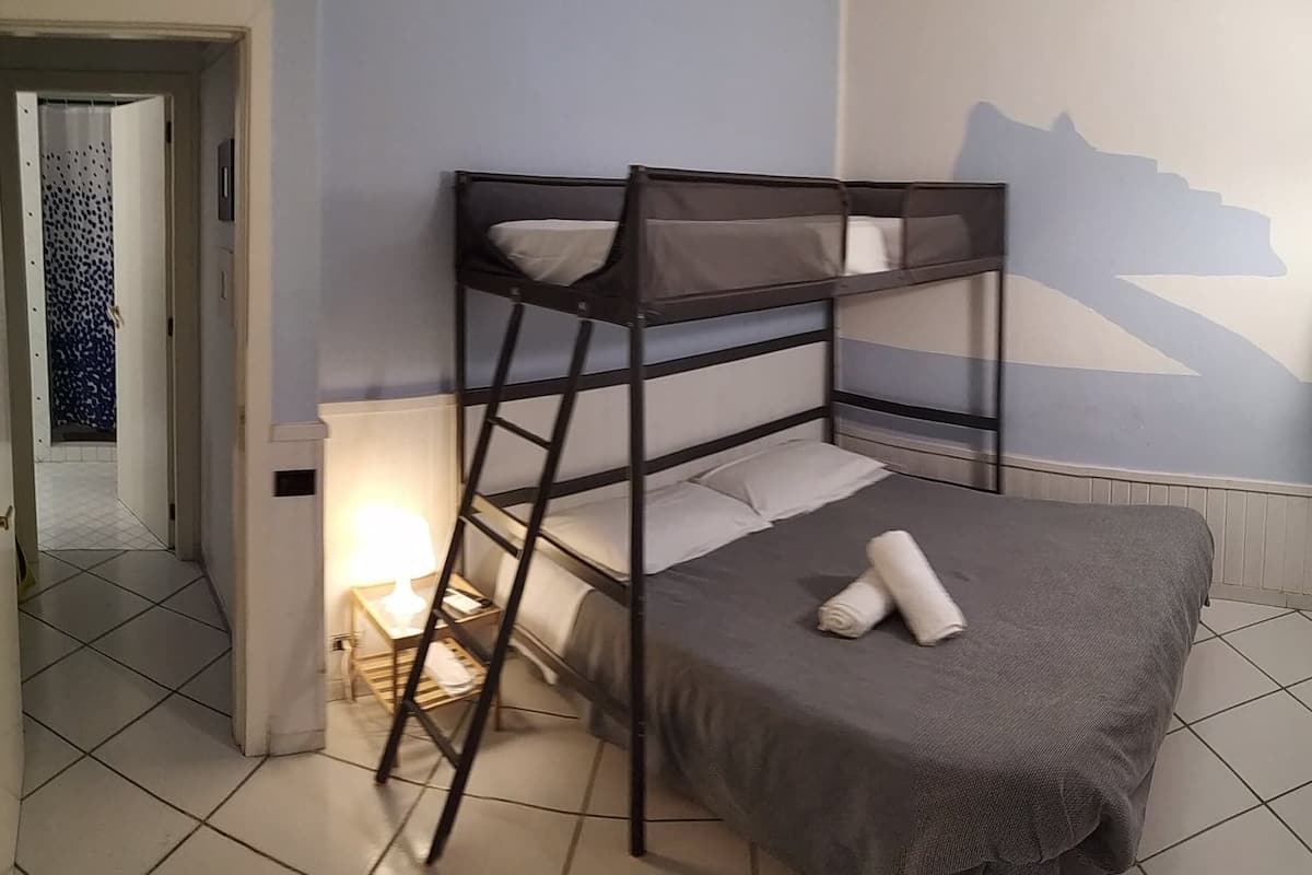 Een stapelbed met een ladder, een bedlampje en een handdoek op het onderste bed.
