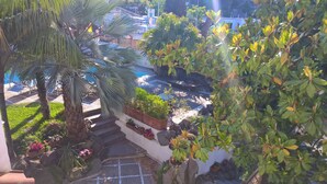 A pool area with steps leading down to a tiled patio, surrounded by various plants and a palm tree. - B&B Villa Cinque Pini (Casamicciola Terme)