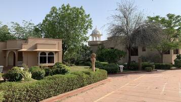 Un patio con un sendero empedrado, un edificio con cúpula y follaje circundante.