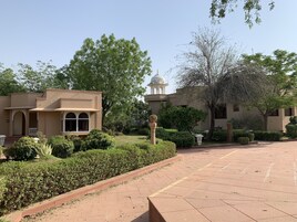 Un patio con un sendero empedrado, un edificio con cúpula y follaje circundante.