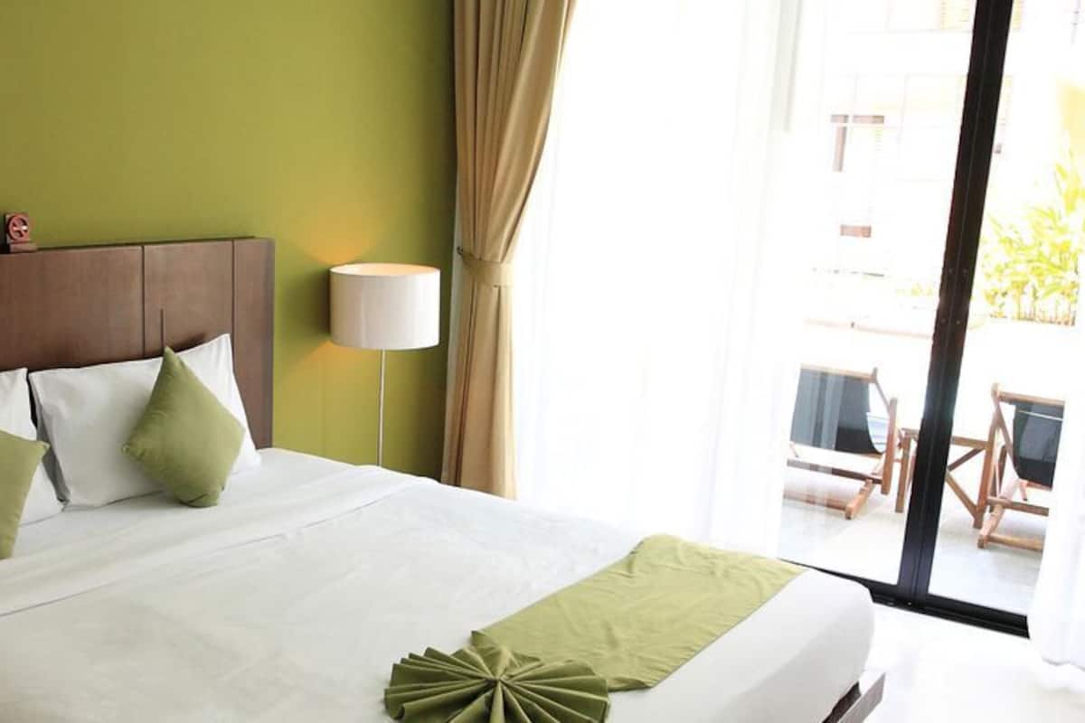 A hotel room with a bed, two pillows, a bedside lamp, and a view of the outdoors.
