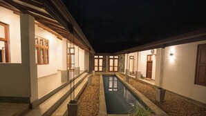 A serene courtyard with a central pool, stone steps, and a covered walkway.