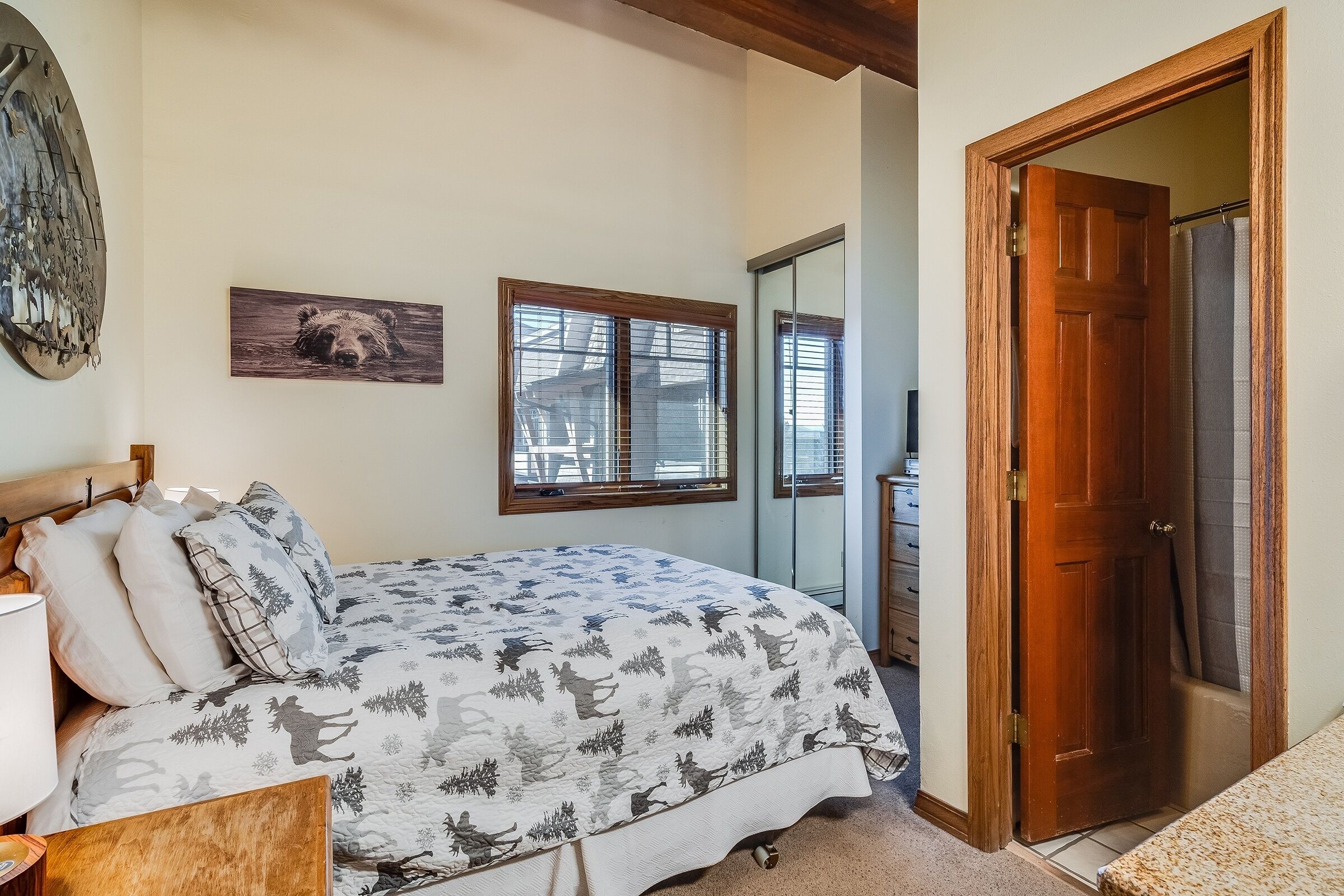 Un dormitorio con una cama, una puerta de madera y una ventana con persianas.