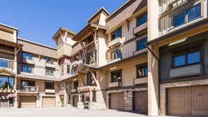 Un immeuble à plusieurs étages doté d’une cour intérieure, d’une façade en pierre et de plusieurs portes de garage.