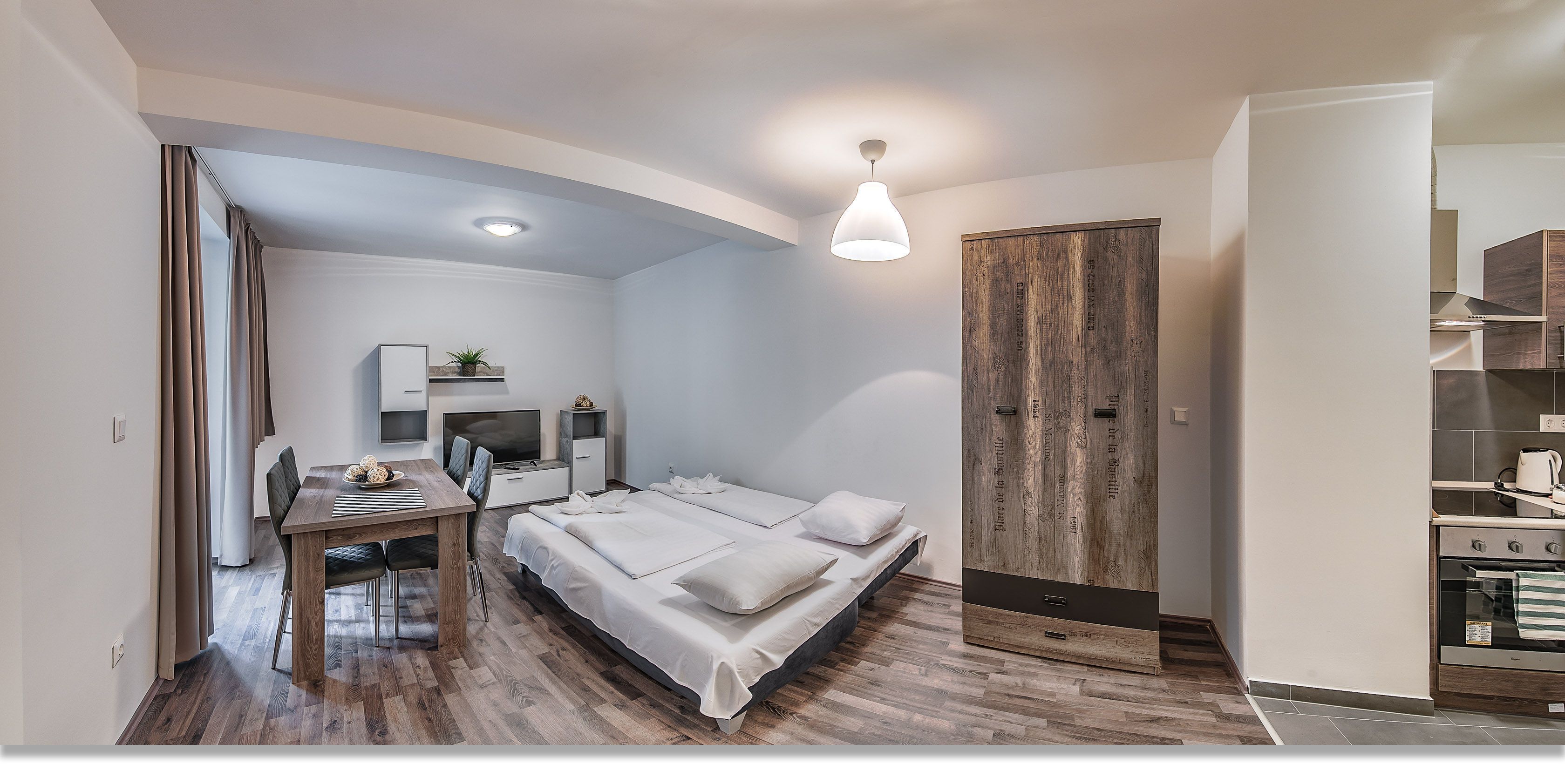 A modern bedroom with a bed, bedside tables, a desk, and a wardrobe.