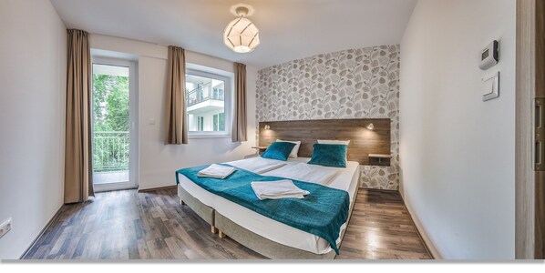 Un dormitorio moderno con una cama grande, cabecera de madera, vista a un balcón y pared con diseño.