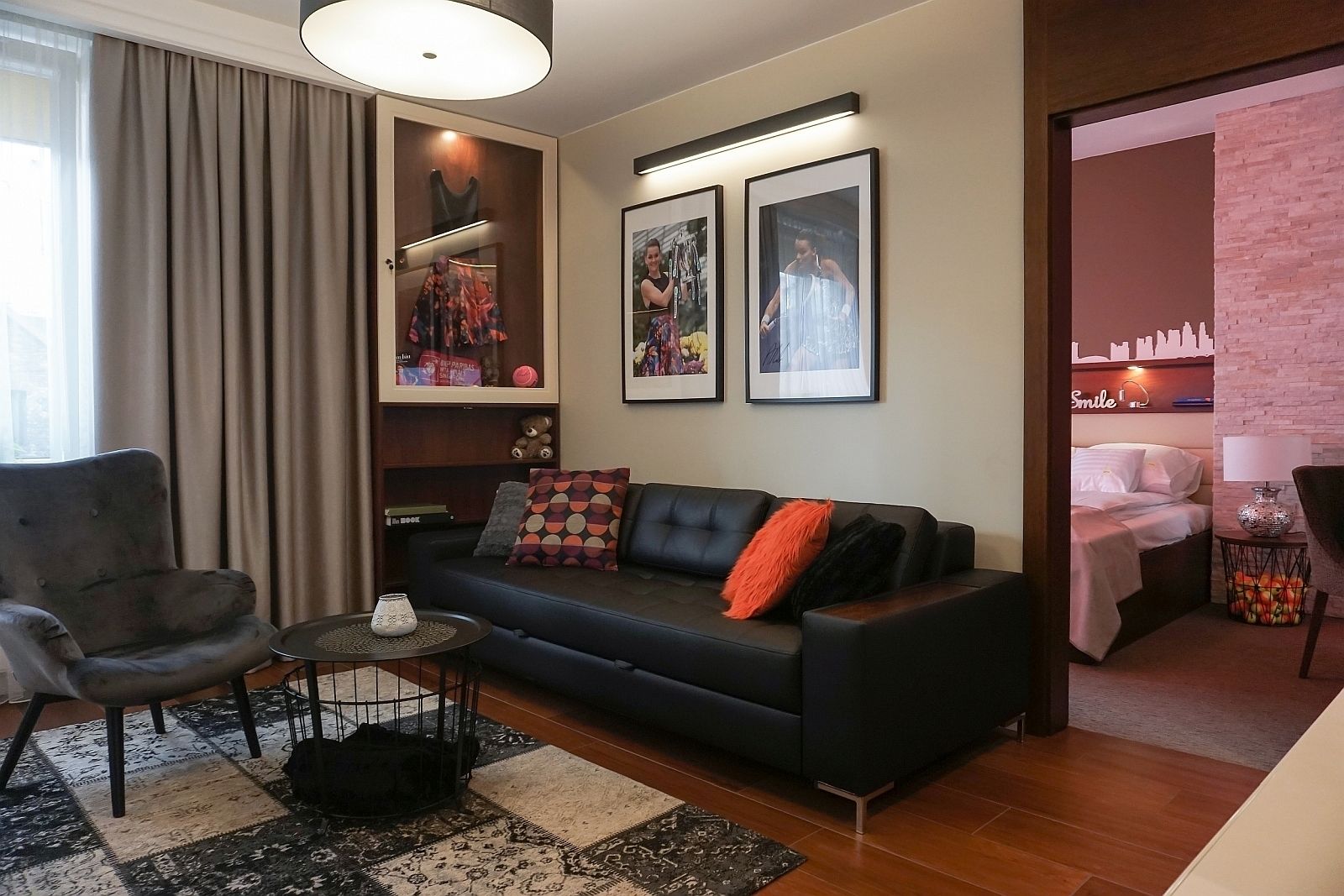Ein modernes Wohnzimmer mit einem dunkelgrauen Sofa, einem runden Couchtisch und einem gemusterten Teppich.