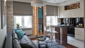 A modern kitchen with a central island, a dining area with a sofa and chairs, and a large window providing natural light. - AGA Tenis Apartments by Radwanska (Kraków)