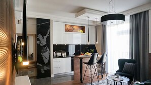 A modern living room with a sofa, a coffee table, and a dining area with chairs and a table. - AGA Tenis Apartments by Radwanska (Kraków)