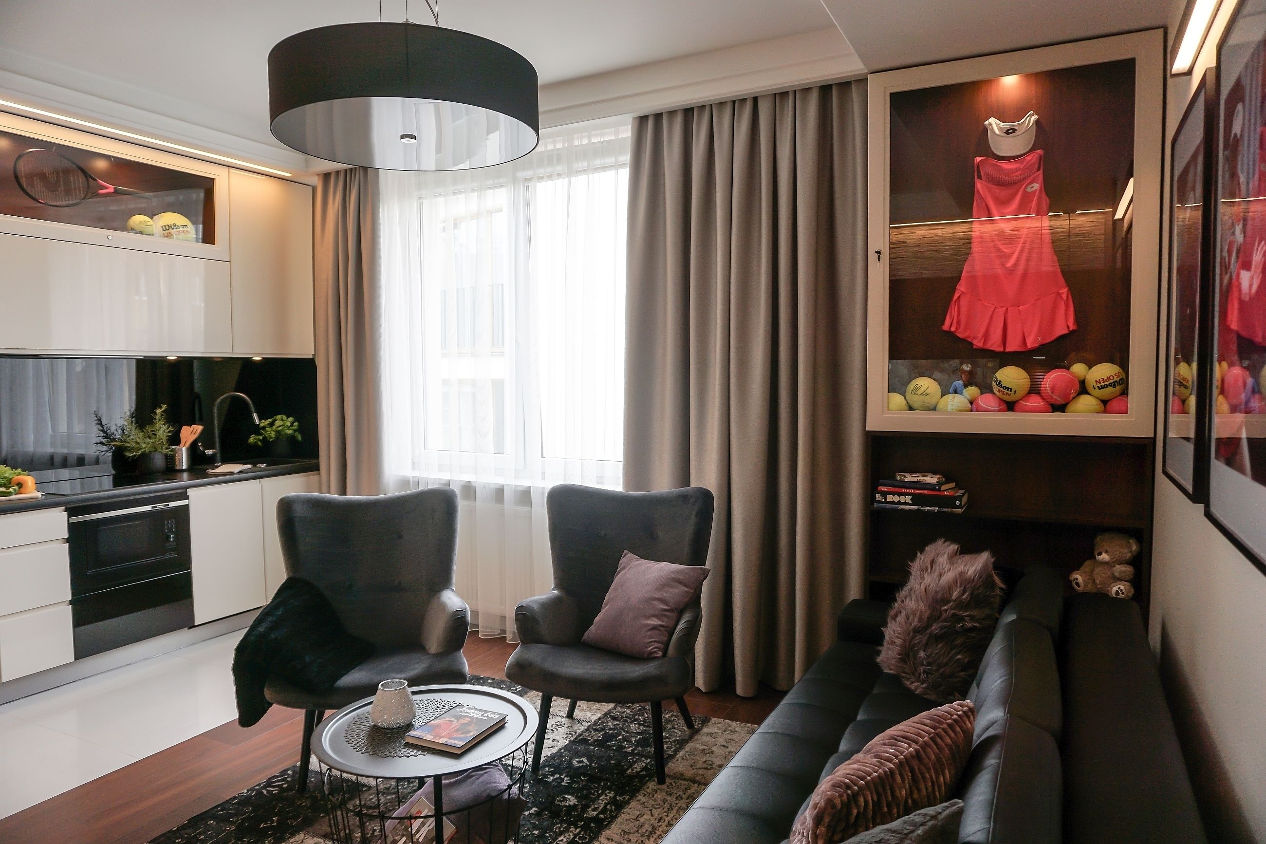 A modern living room with a sofa, two armchairs, a coffee table, and a dining area with a kitchen in the background.