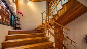 A wooden staircase with a handrail and a small shelf with a potted plant. - Anumat Premium Budget Hotel (Chiang Mai)