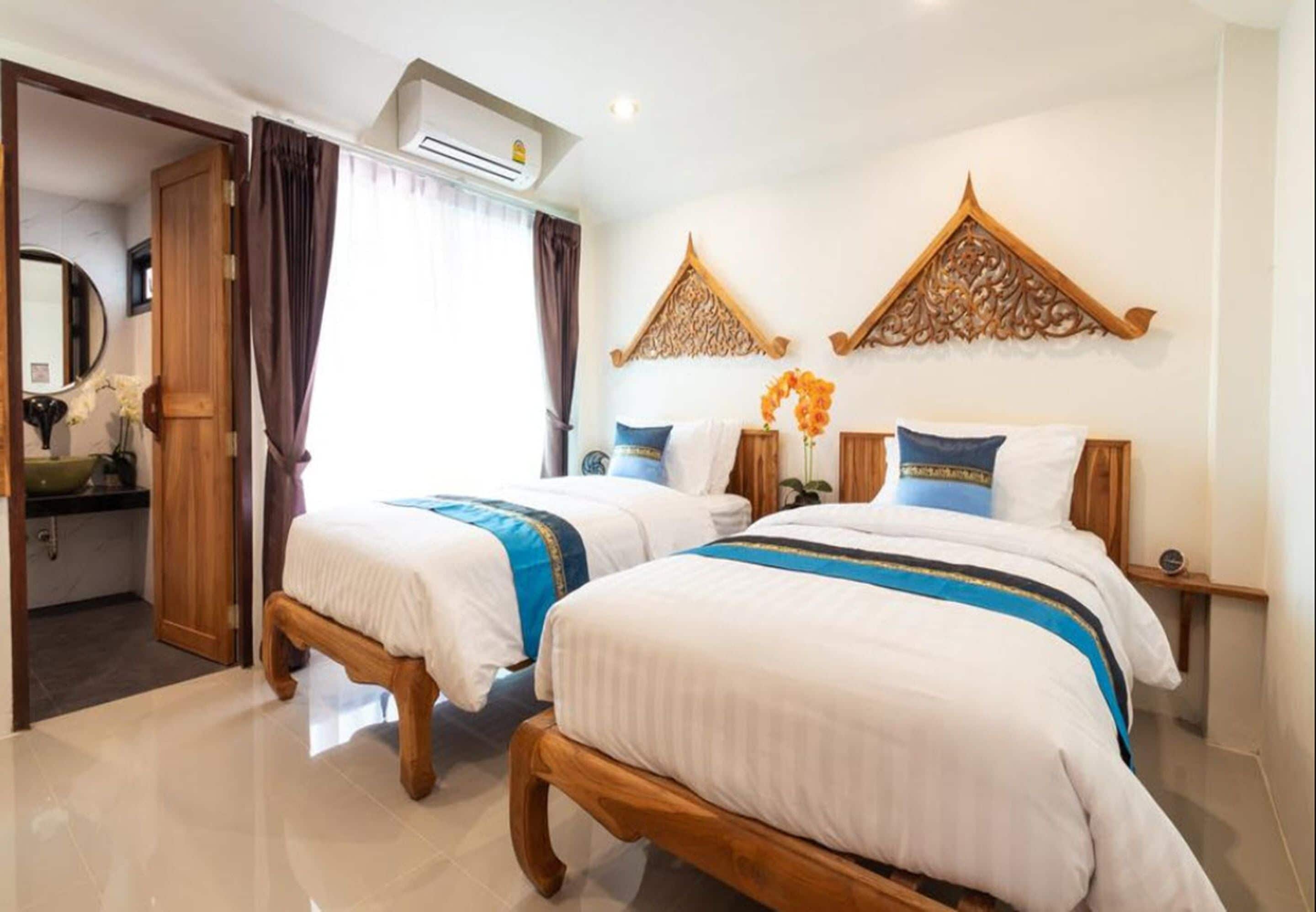 A hotel room with two beds, a wooden headboard, a mirror, and a decorative wall panel.