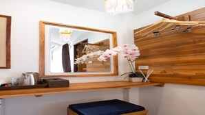A bathroom with a wooden vanity, a mirror, a sink, a blue bench, and a potted orchid. - Anumat Premium Budget Hotel (Chiang Mai)